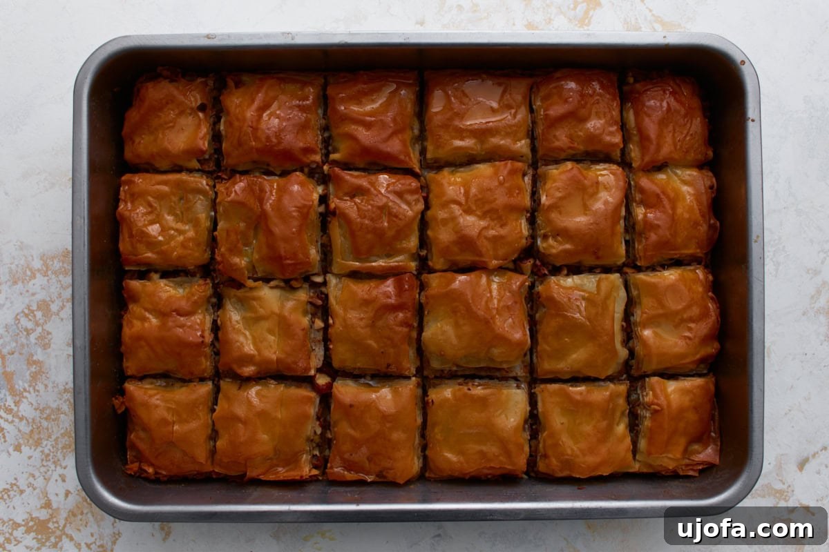 Hot baked gluten-free baklava in a pan after pouring honey syrup over the top.