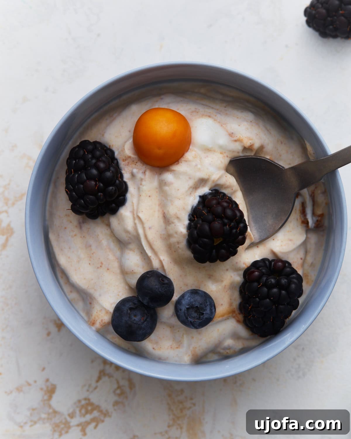 Velvety Vegan Fruit Dip 2 Dairy-free fruit dip topped with blackberries, blueberries, and a golden berry in a small bowl.