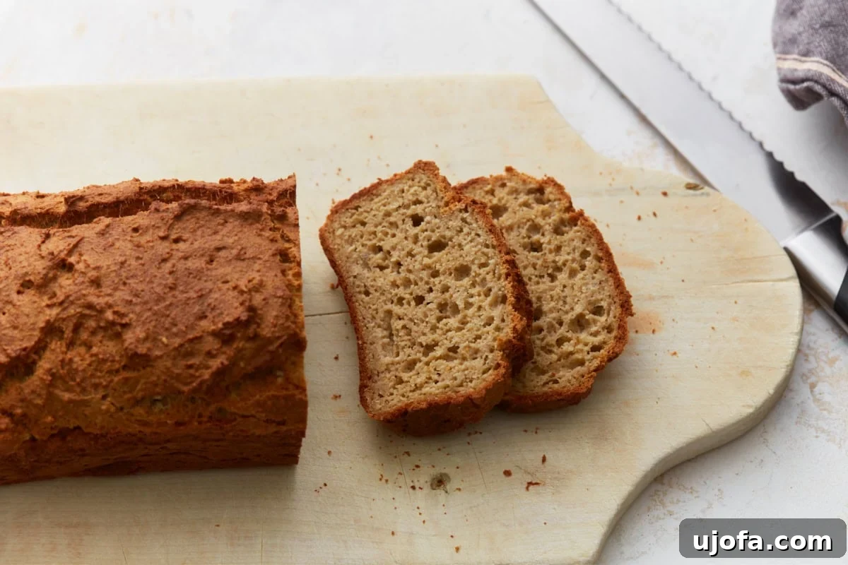 Wholesome Oat Bread 9 Oat flour bread loaf with two slices cut on a wooden cutting board with visible crumb texture