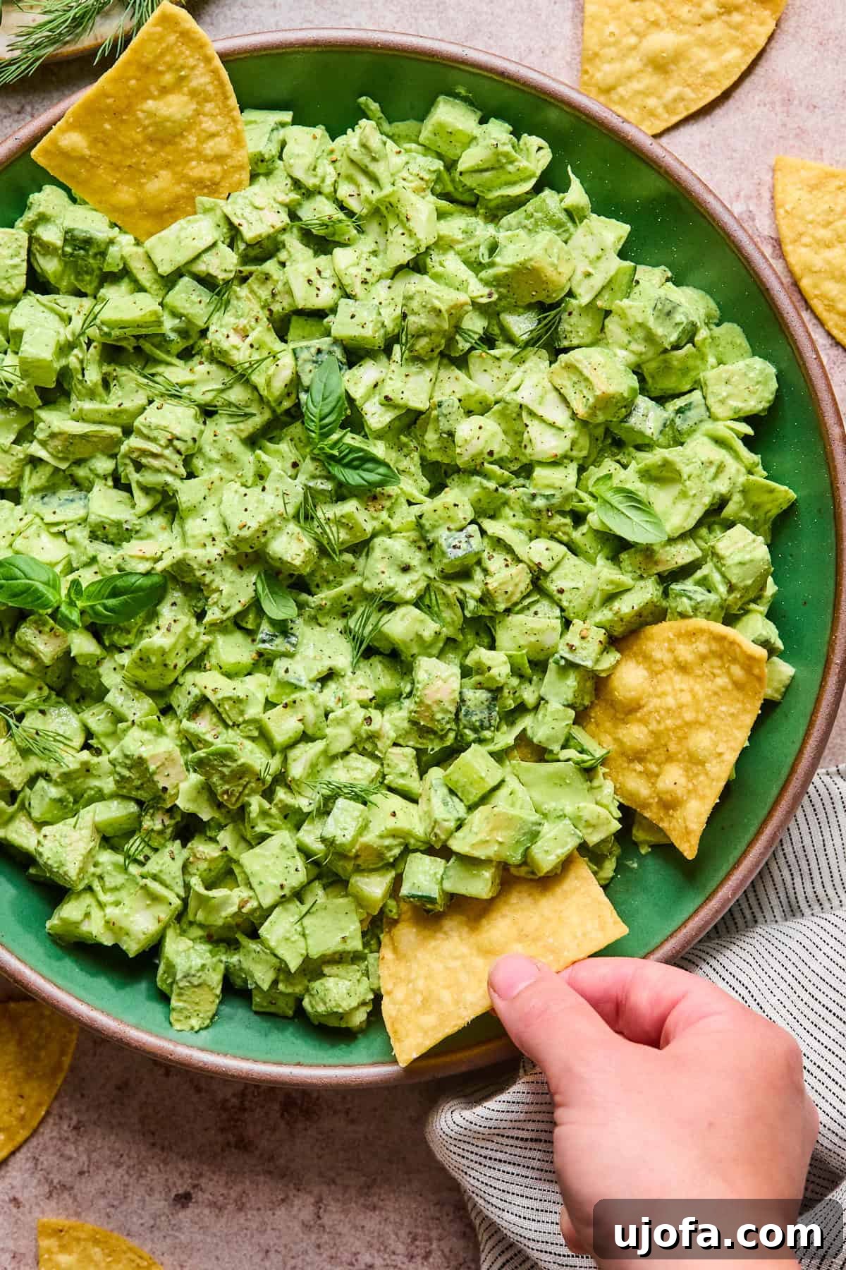 Green Goddess Chicken Salad with Extra Protein Boost 7 a hand dipping a chip into green chicken salad