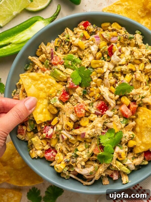 Green Goddess Chicken Salad with Extra Protein Boost 9 Mexican street corn chicken salad in a bowl with a hand holding a chip scooping out a bite