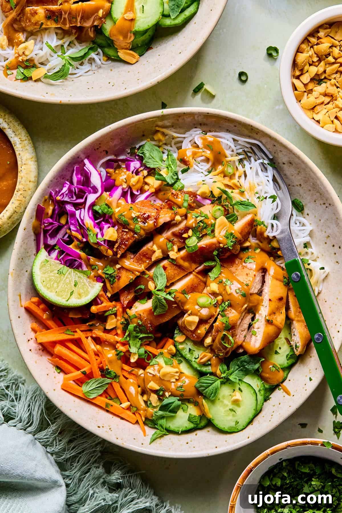 Spring roll in a bowl topped with fresh basil and halved lime slices, with a fork resting inside the bowl.