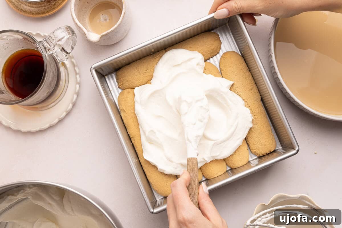 Gluten-Free Tiramisu Recipe: Authentic Italian Dessert Without Gluten 7 whipped cream being spread on lady fingers in a pan