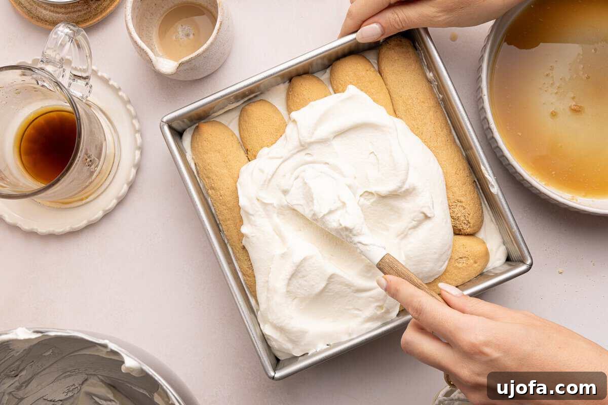Gluten-Free Tiramisu Recipe: Authentic Italian Dessert Without Gluten 8 whipped cream being spread on lady fingers in a baking pan