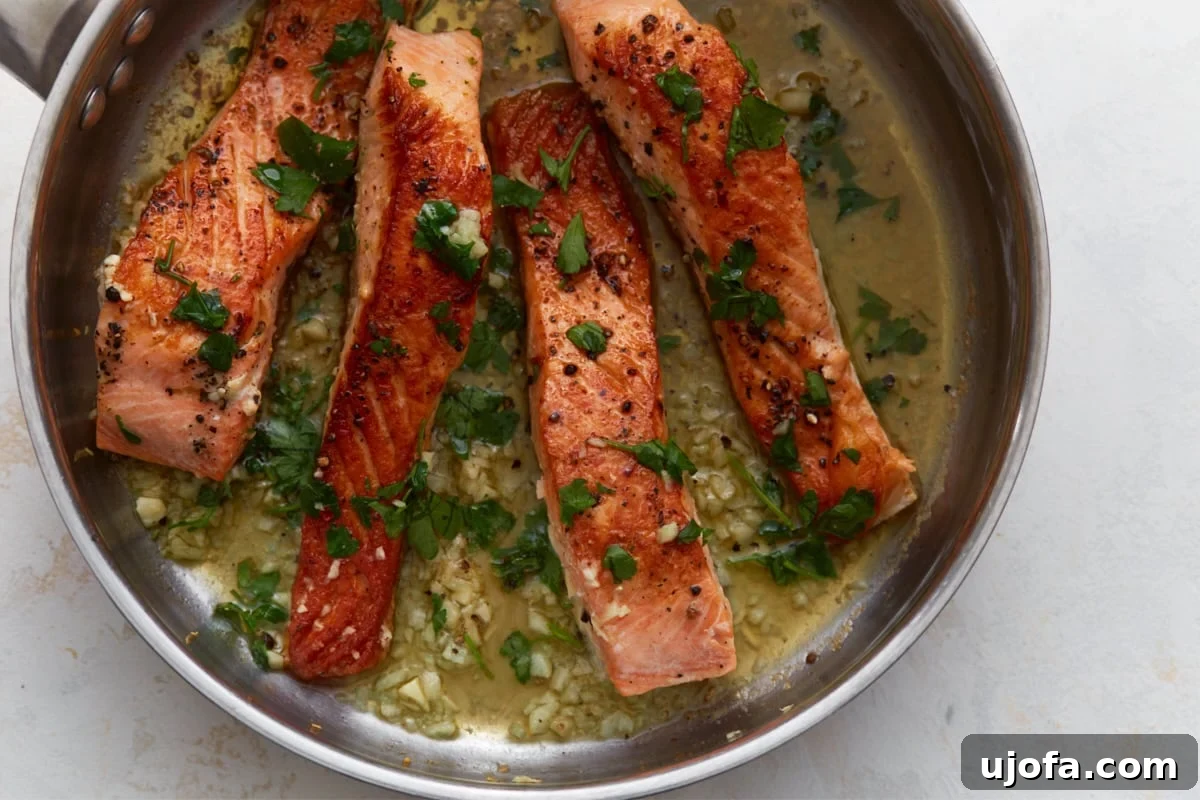 Keto Salmon in Garlic Butter Lemon Sauce 8 Keto salmon finished with garlic butter sauce and fresh parsley in skillet