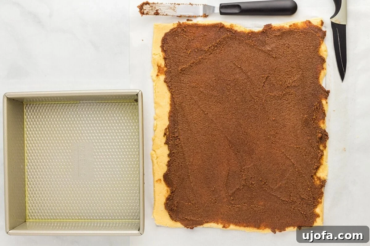 Keto cinnamon roll dough rolled into a rectangle and spread with cinnamon sugar filling before rolling