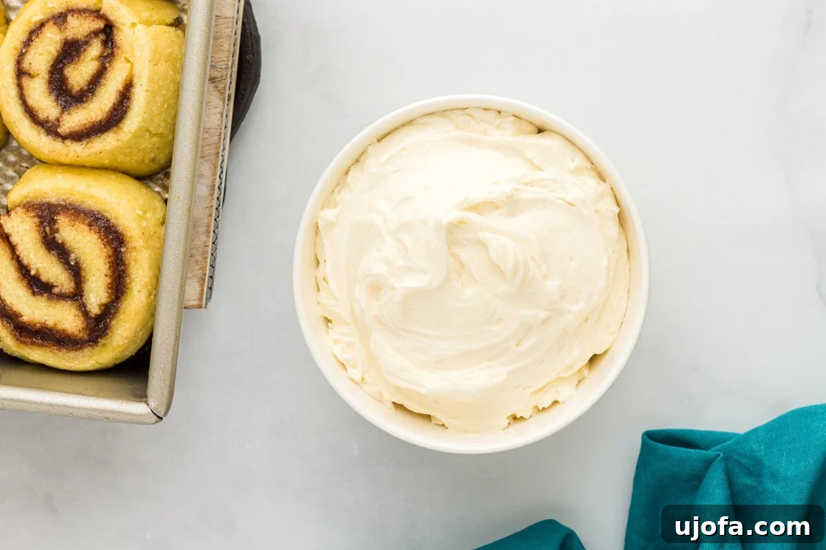 Cream cheese frosting in a bowl next to baked keto cinnamon rolls