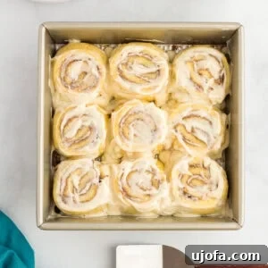 Keto cinnamon rolls in a baking pan topped with cream cheese frosting