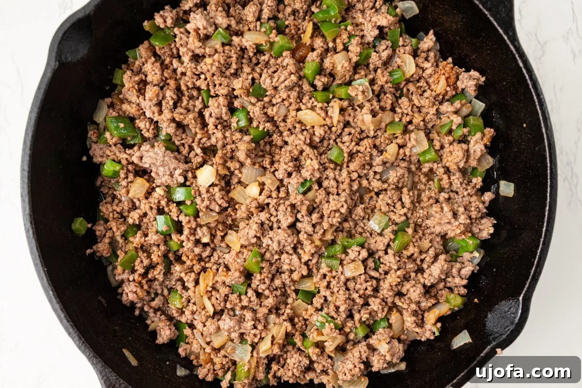 Seasoned ground beef mixture with onions and peppers cooking in skillet