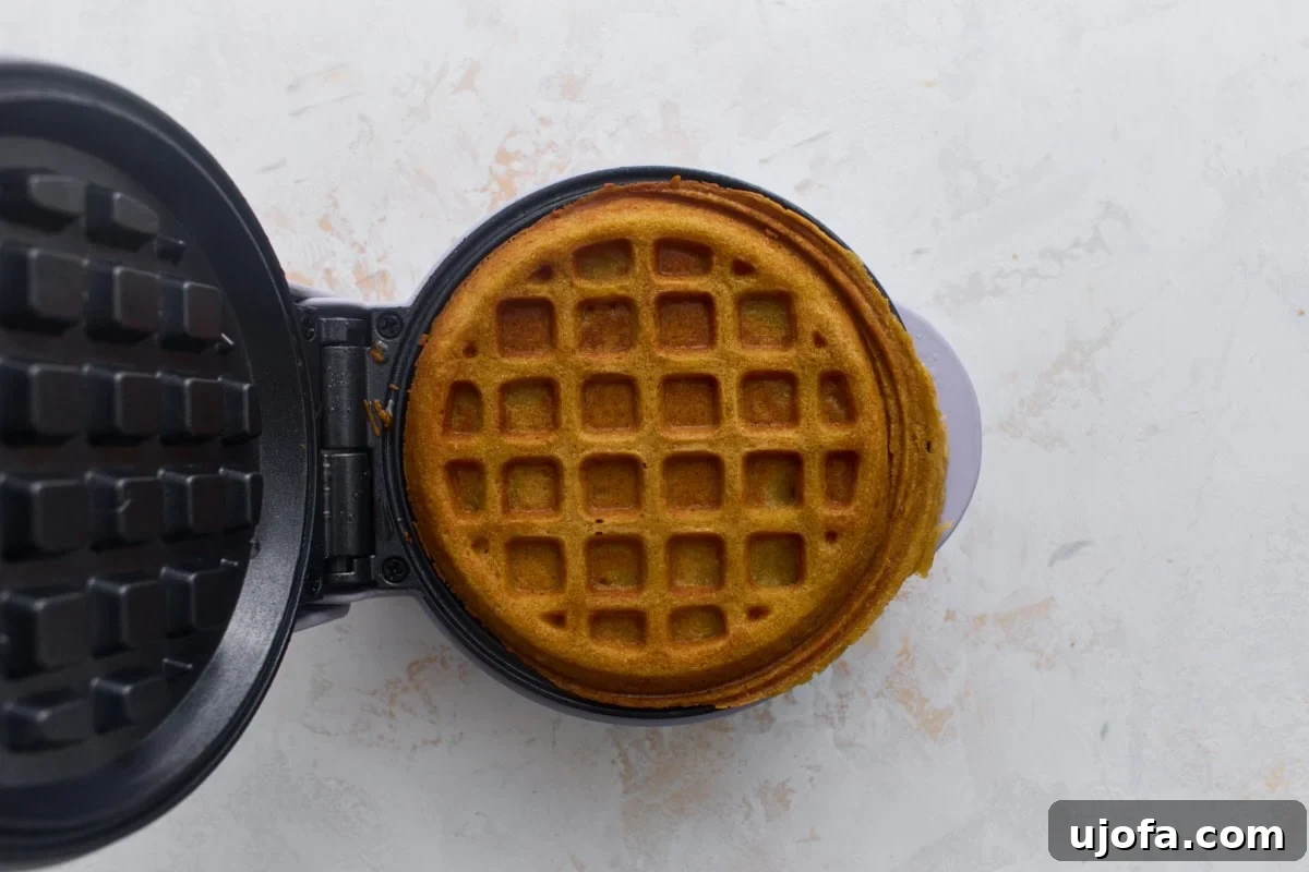 Crispy Oat Flour Waffles Recipe for Fluffy Homemade Waffles 9 Golden brown oat flour waffle cooking in a waffle maker.