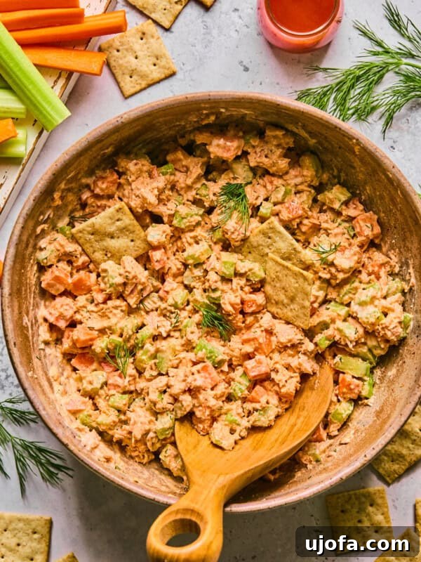 Gluten-Free Italian Pasta Salad Recipe for Flavorful Picnics 9 buffalo tuna salad in a pink bowl with a wooden spoon surrounded by crackers and ingredients