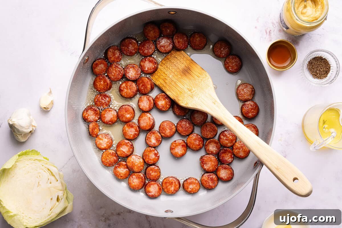 sausage in a skillet with a wooden spoon