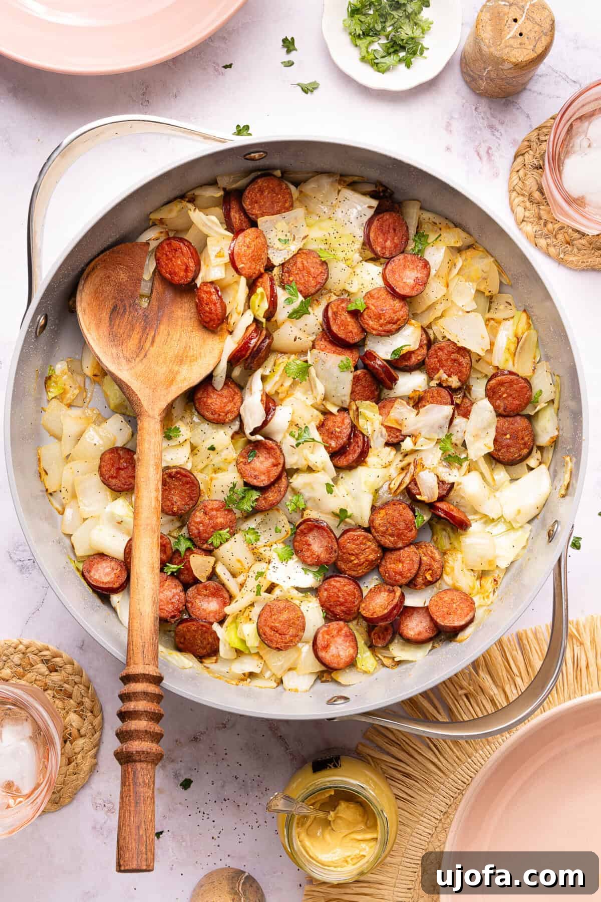 sausage and cabbage in a skillet with a wooden spoon