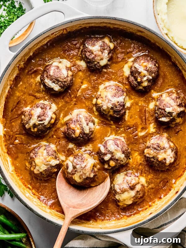 french onion meatballs in a skillet with a wooden spoon