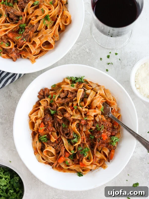 Short rib ragu with parsley in a white bowl with a fork