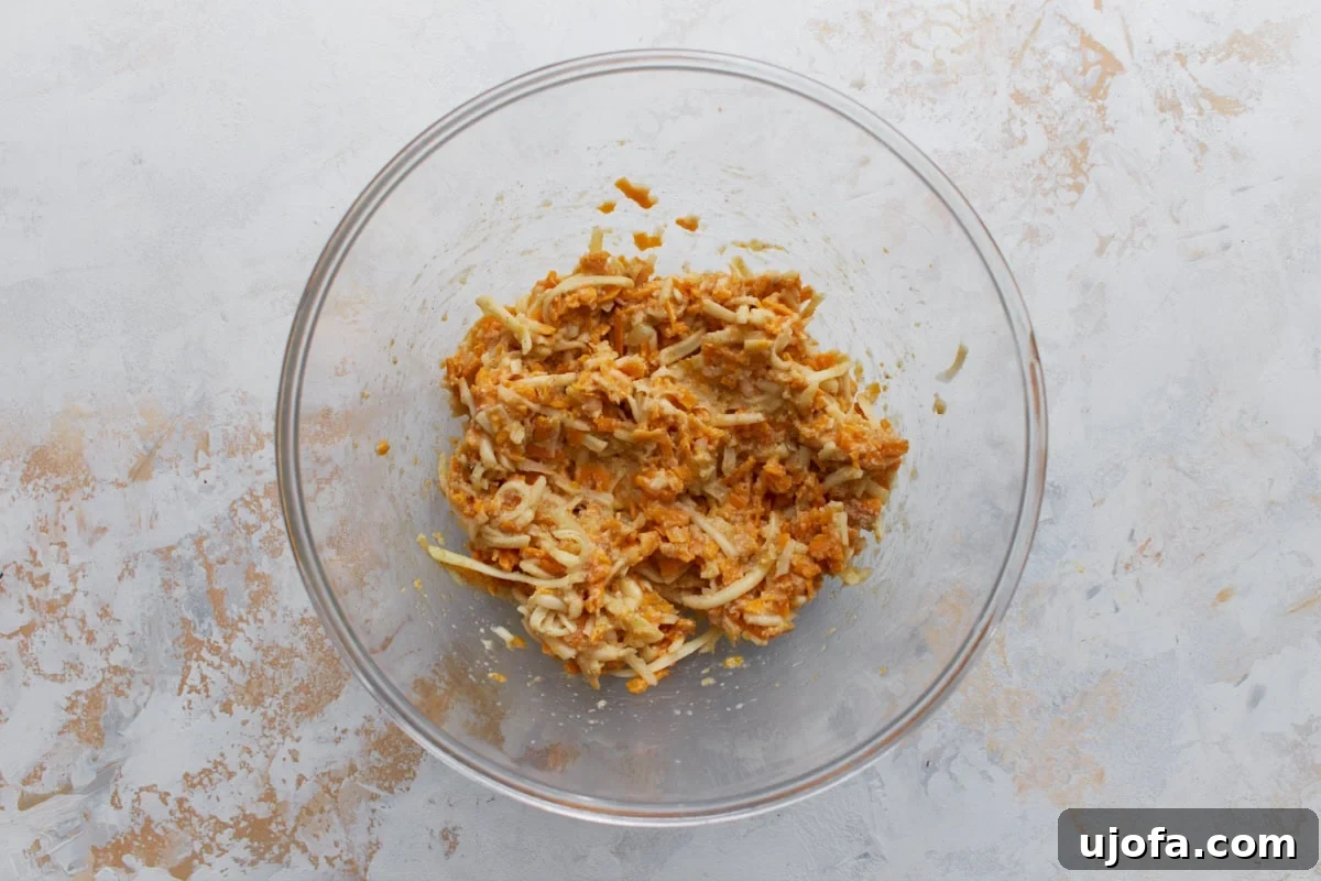 Cheese and egg mixture combined in a glass bowl for crustless tomato pie filling.