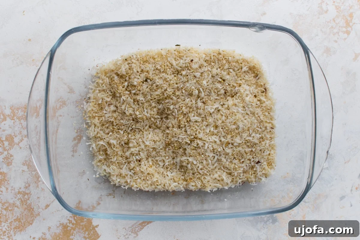 Parmesan, almond flour, and seasoning mixture in a glass dish for breading keto zucchini fries.