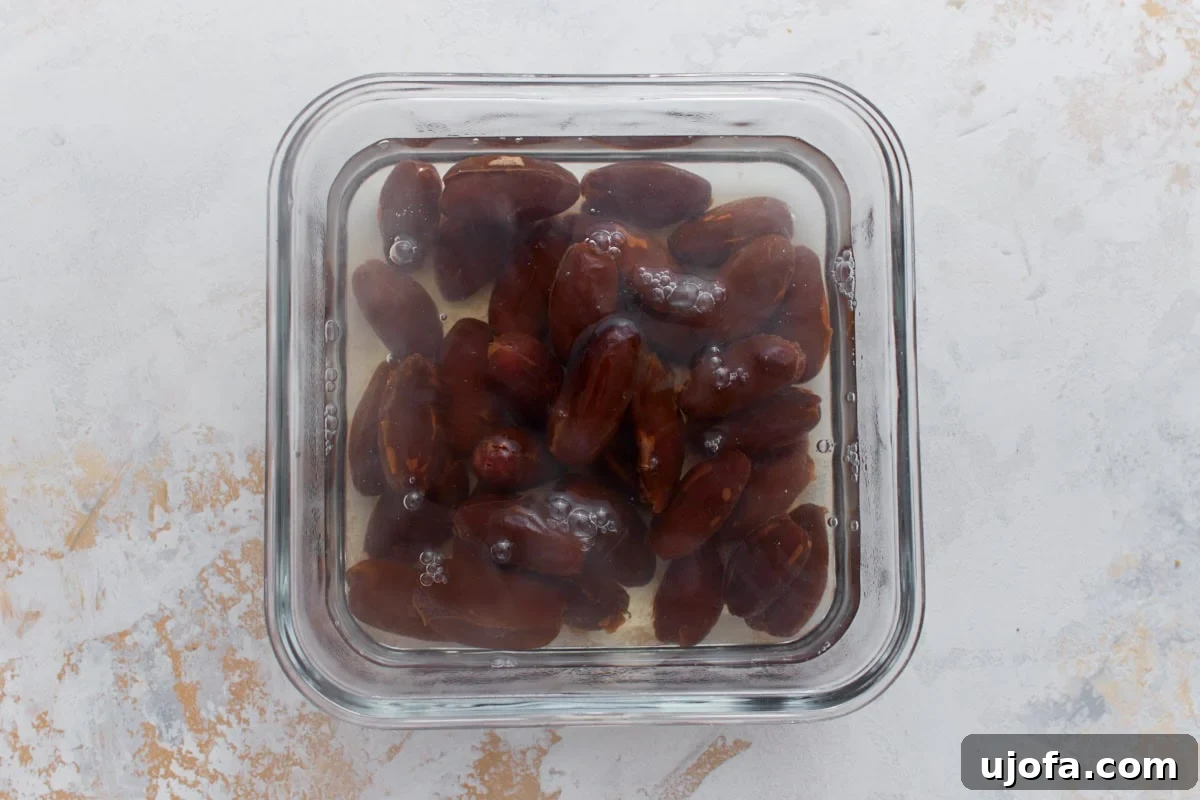 Pitted dates soaking in hot water in a glass container before blending for homemade date ice cream.