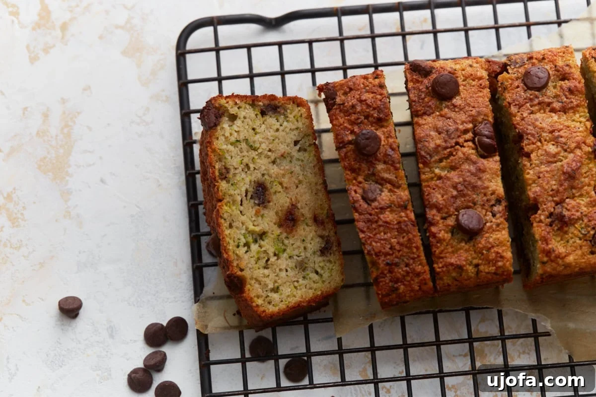 Close up of sliced almond flour zucchini bread with chocolate chips on a black wire rack with chocolate chips scattered around