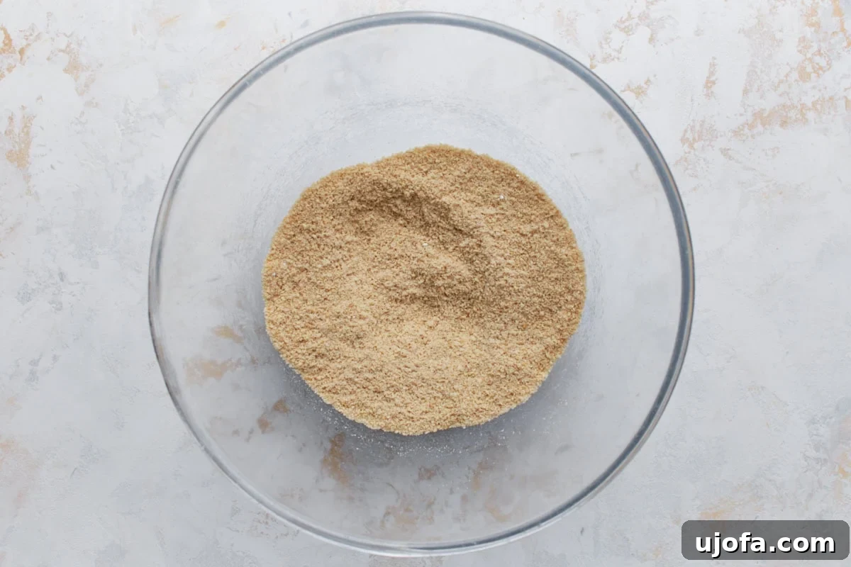 Overhead view of almond flour and dry ingredients combined in a glass mixing bowl