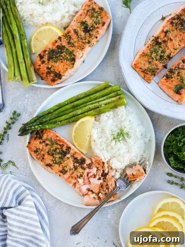 Protein-Packed Salmon Caesar with Creamy Dressing 16 three plates of garlic herb salmon on a white plate with asparagus, white rice, and a lemon wedge
