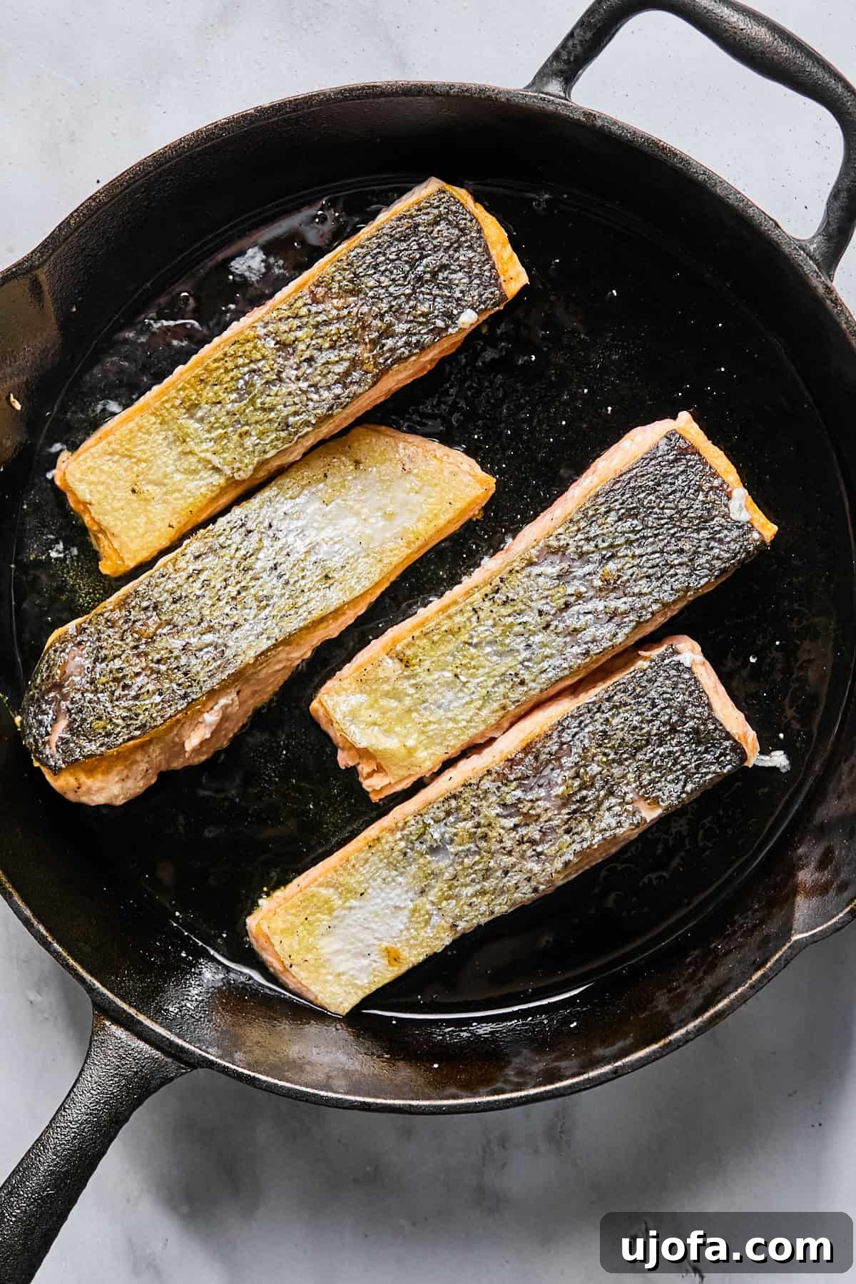 Protein-Packed Salmon Caesar with Creamy Dressing 7 salmon in a cast iron skillet, skin-side up