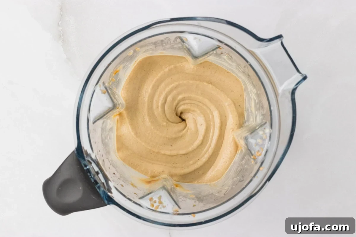 Overhead view of blended banana peanut butter nice cream mixture in a blender showing a thick, creamy swirl texture