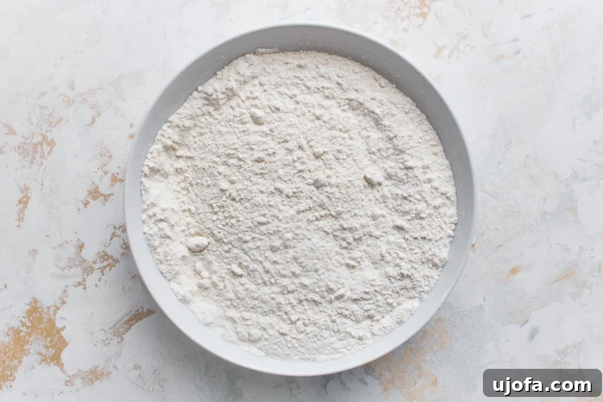 Classic Gluten-Free Victoria Sponge Cake Recipe 5 Gluten-free flour, baking powder, and salt whisked together in a white mixing bowl