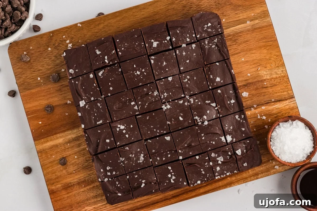 Rich Gluten-Free Dairy-Free Chocolate Fudge Recipe 10 Gluten-free dairy-free chocolate fudge cut into 36 squares on a wood cutting board, sprinkled with flaky sea salt