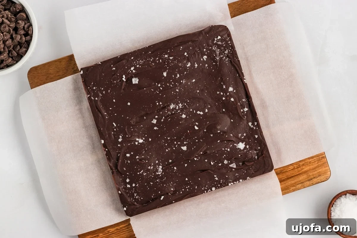 Rich Gluten-Free Dairy-Free Chocolate Fudge Recipe 9 Set chocolate fudge lifted out of the pan on parchment paper and placed on a wood cutting board