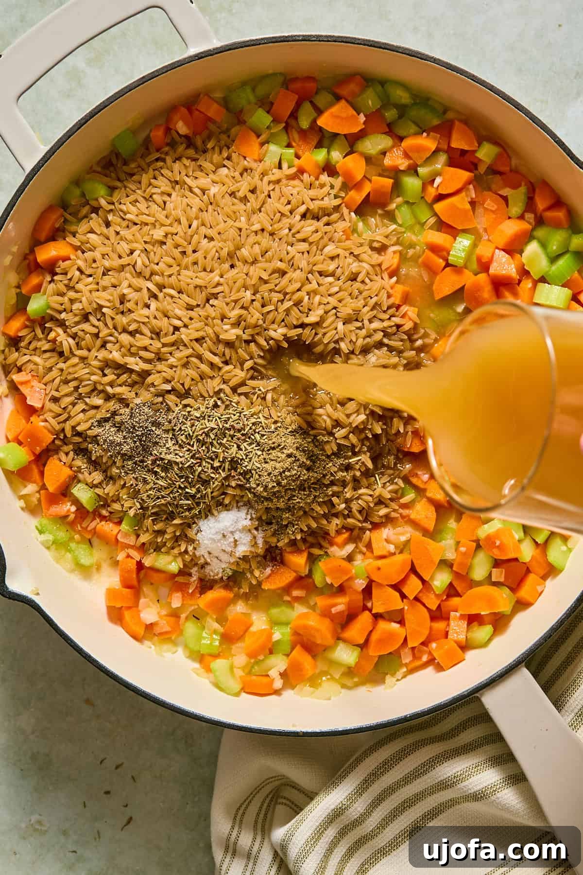 One-Pan Chicken Pot Pie Orzo 6 Orzo, sage, thyme, rosemary, salt, and pepper added to a large skillet with softened vegetables as broth is poured in.