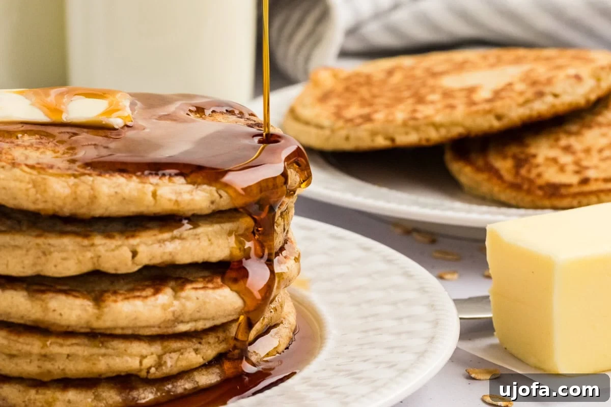 Fluffy Oat Flour Pancakes Recipe 10 Maple syrup pouring over a stack of buttered oat flour pancakes.