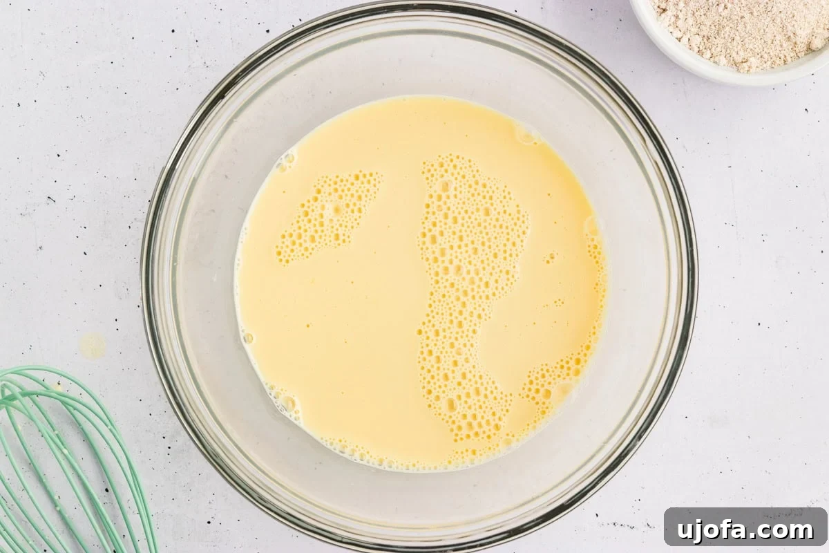 Fluffy Oat Flour Pancakes Recipe 4 Milk, eggs, and vanilla whisked together in a glass bowl for oat flour pancake batter.