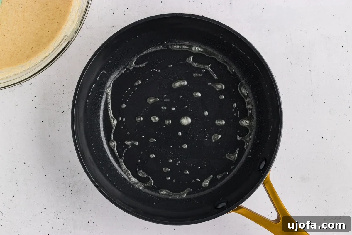 Fluffy Oat Flour Pancakes Recipe 7 Melted butter coating a black skillet before cooking oat flour pancakes.