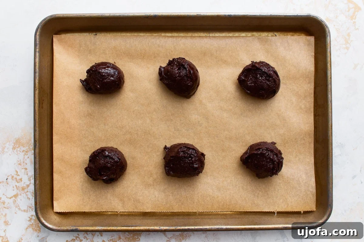 Fudgy Flourless Chocolate Cookies Gluten Free 9 Six scoops of flourless chocolate cookie dough spaced on a parchment-lined baking sheet, ready to bake.
