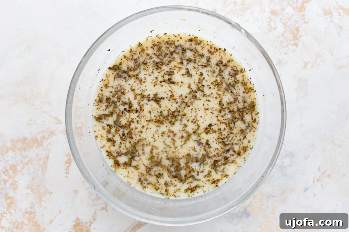 Dairy-Free Marry Me Chicken with Sun-Dried Tomato Sauce 8 Chicken broth and coconut milk whisked together with nutritional yeast, cornstarch, and dried oregano in a glass bowl.