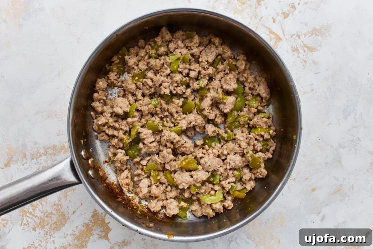 Crustless Pizza Bowl Recipe: Cheesy Pepperoni and Marinara 5 Browned Italian sausage and green bell pepper cooking in a skillet.