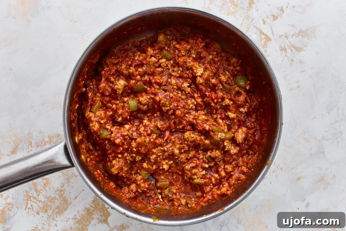 Crustless Pizza Bowl Recipe: Cheesy Pepperoni and Marinara 6 Italian sausage simmering in marinara sauce with Italian herbs in a skillet.