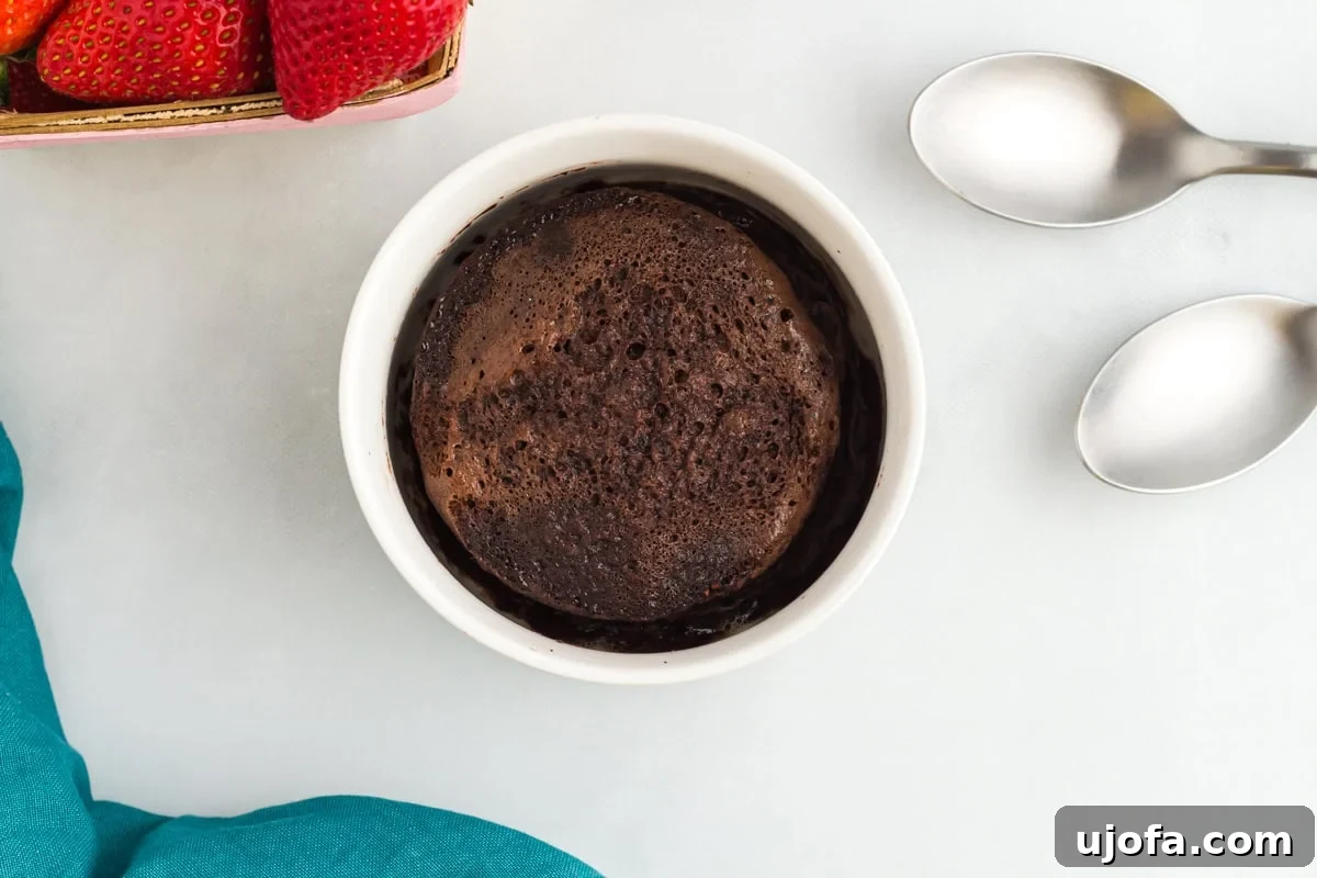 Microwave Flourless Chocolate Mug Cake 5 Flourless mug cake in a white ramekin next to fresh strawberries and two spoons